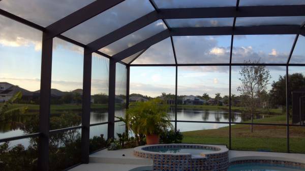 Screened pool and spa overlook a pond and golf course at dusk.