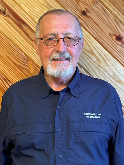 Screenmasters team member in a navy branded button-up shirt, portrait against a wood-plank backdrop.